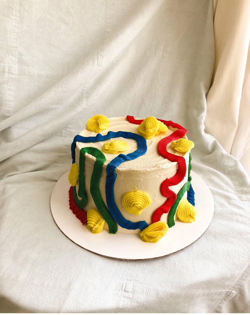 Celebration cake — caramel buttercream with coffee beans, green and red piped folk pattern