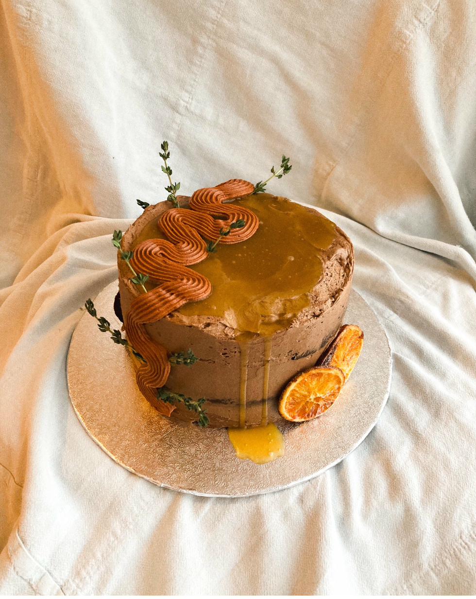Celebration cake — chocolate buttercream with caramel drip, piped waves, dried orange slices and fresh thyme