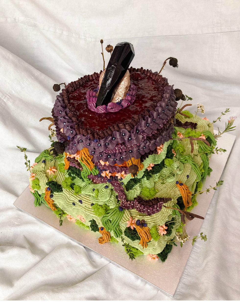 Celebration cake — cream and purple buttercream flowers on pale yellow with gold details