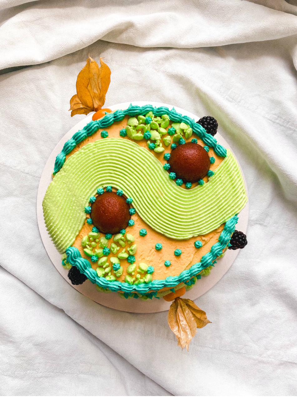 Celebration cake — three-tier square wedding cake with cream buttercream, orange and green piped waves, blackberries