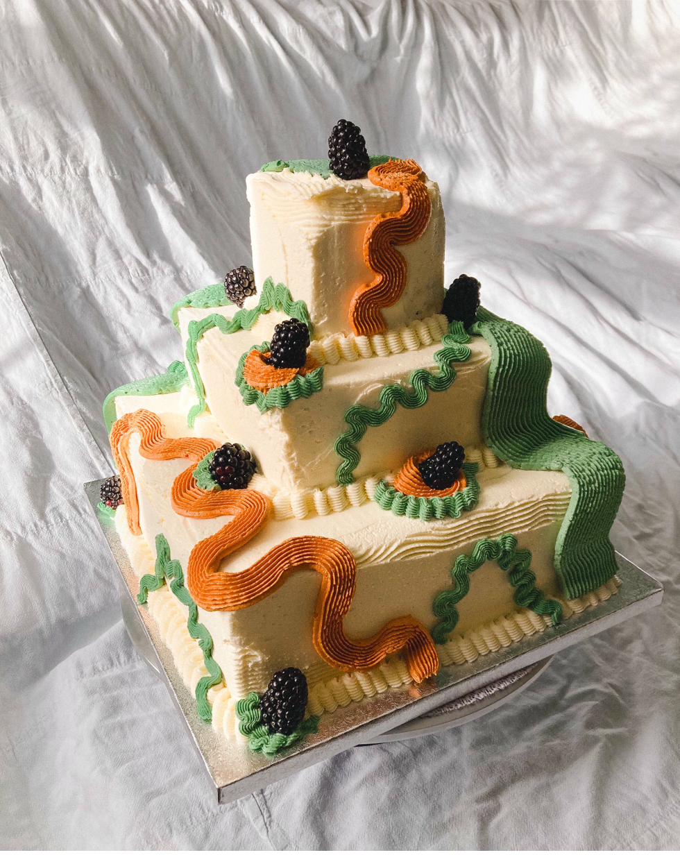 Celebration cake — vivid red and orange buttercream with grapes, blueberries, raspberries and metallic sprinkles